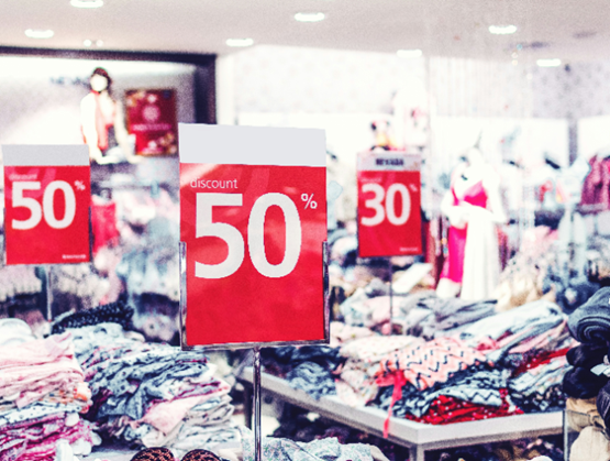 Red discount signs showing 50% and 30% in a busy clothing store during a sales event