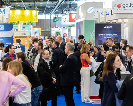  Vue animée des allées d’un salon professionnel avec de nombreux visiteurs en discussion autour des stands d’exposants.