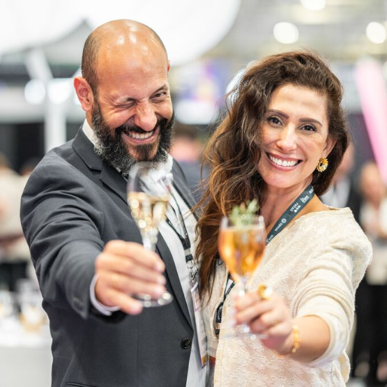 Deux participants souriants trinquent avec des verres lors d’une soirée de networking professionnelle.