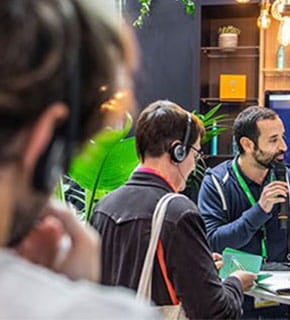 Journaliste réalisant une interview avec un micro dans un espace lumineux et végétalisé lors du salon.