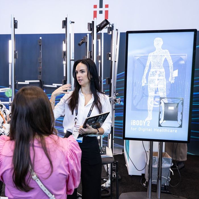 Présentatrice sur un stand de la zone Innovators Showcase du NRF Retail's Big Show, présentant une innovation en santé numérique avec un écran.
