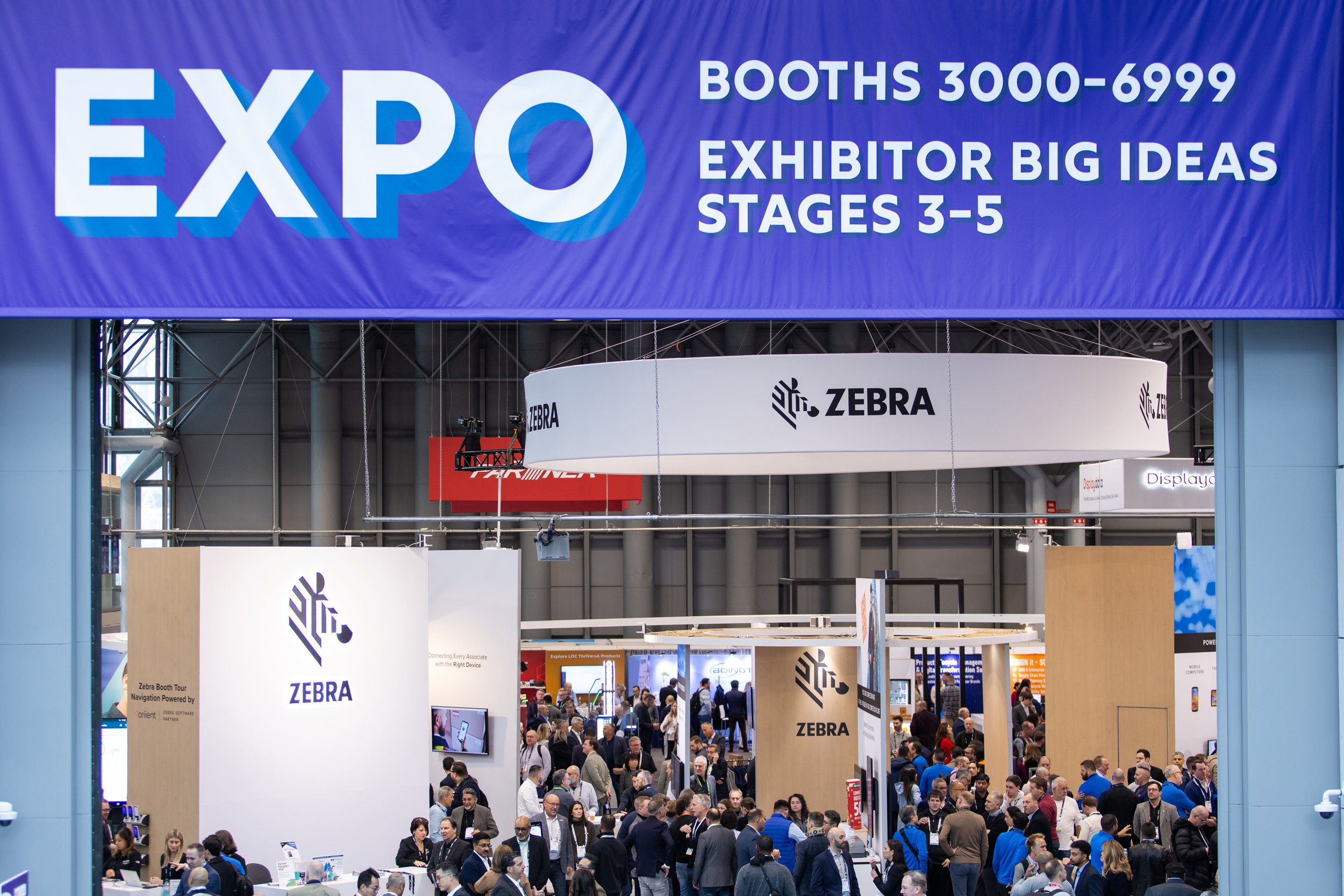 Expo hall view at NRF 2025 with a crowd in front of the Zebra Technologies booth, under a large "EXPO" banner.