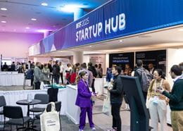 Vue du Startup Hub à NRF 2025 avec des visiteurs échangeant avec des exposants tech.
