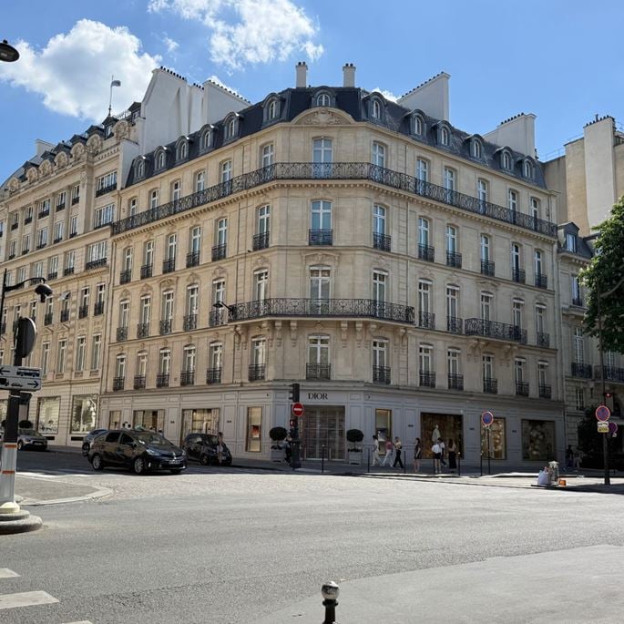 Dior store facade on a Parisian avenue, located in an elegant Haussmann-style building.