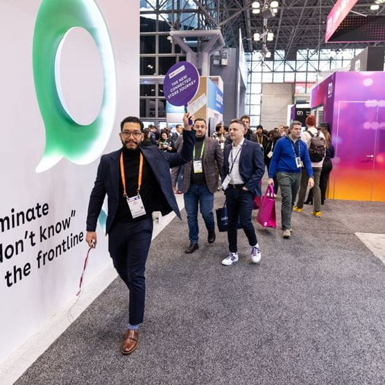 A group of attendees walks through the aisles of NRF 2025, led by a participant holding up a 'The New Connected Store Journey' sign.